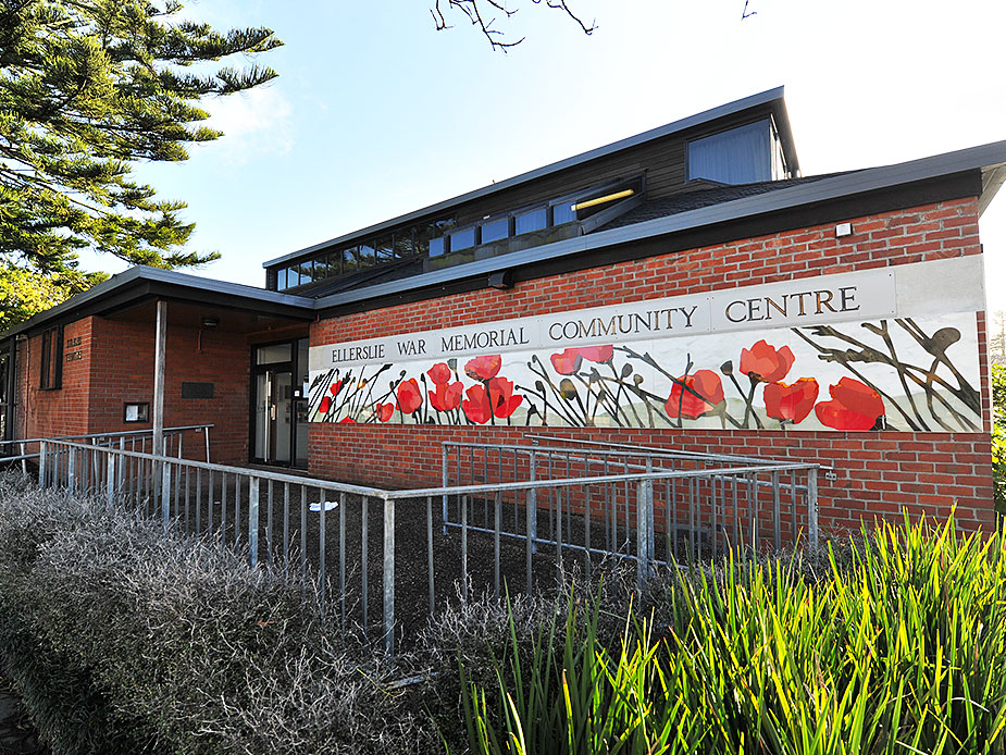 Brick community centre building with painted poppy mural across the facade