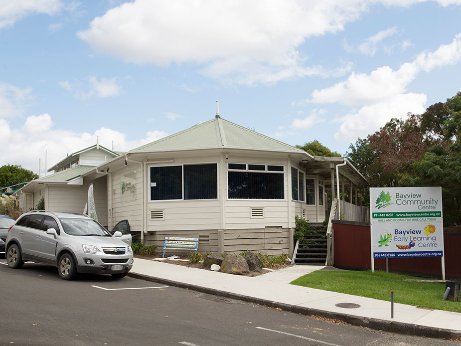 Single-storey weatherboard community centre with a bay-window extension and signage on the street