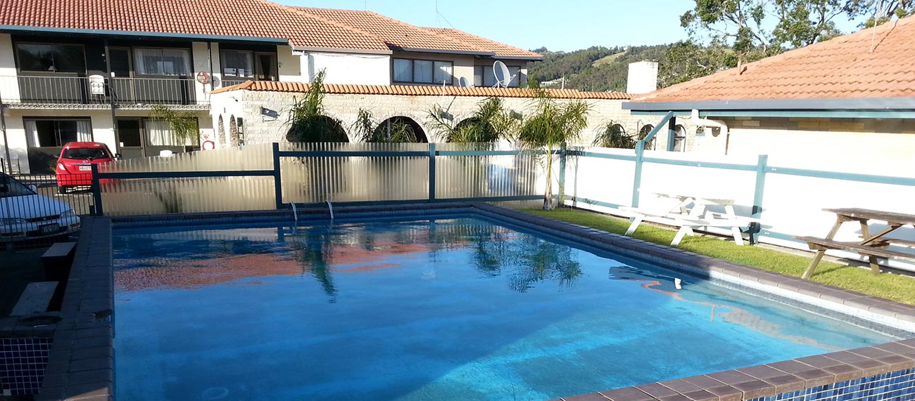 Outdoor swimming pool with motel building and hills in the background