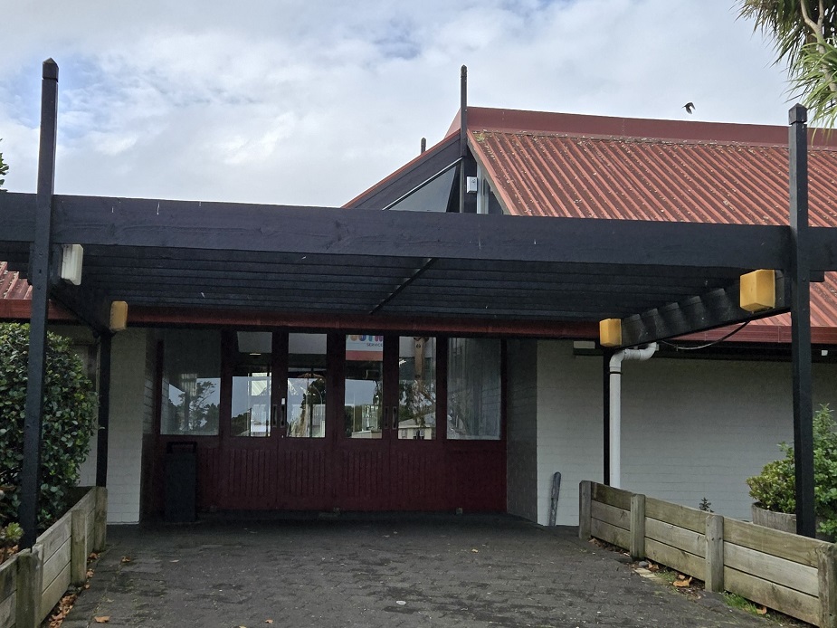 Low community centre building with red corrugated roof and covered entrance
