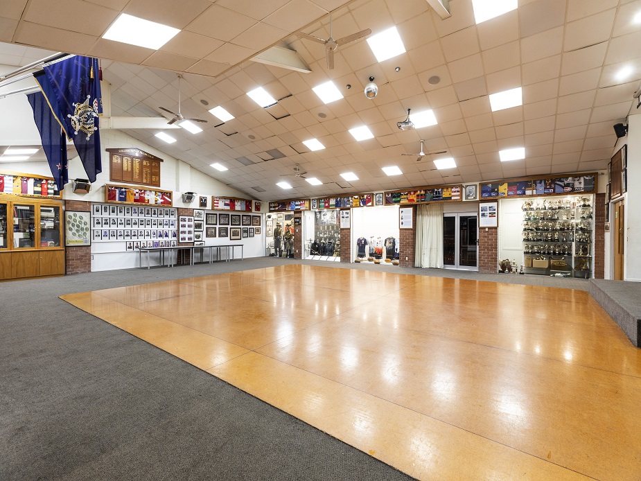 Large function room with dance floor, trophies on display, and club memorabilia on walls