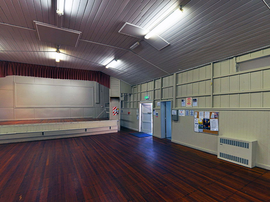 Main hall interior with raised platform, dark timber walls and polished floor