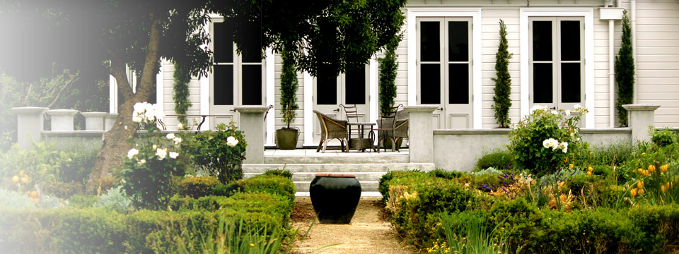 White heritage homestead with a formal parterre garden, columnar cypress trees and rose borders