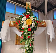 Flower arrangement on a cross with white fabric drape