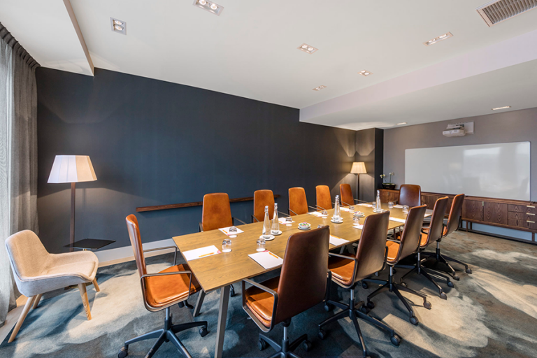 Hotel meeting room with long table, leather chairs, and dark feature wall