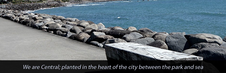 Rocky coastal seawall with ocean beyond, text overlay below