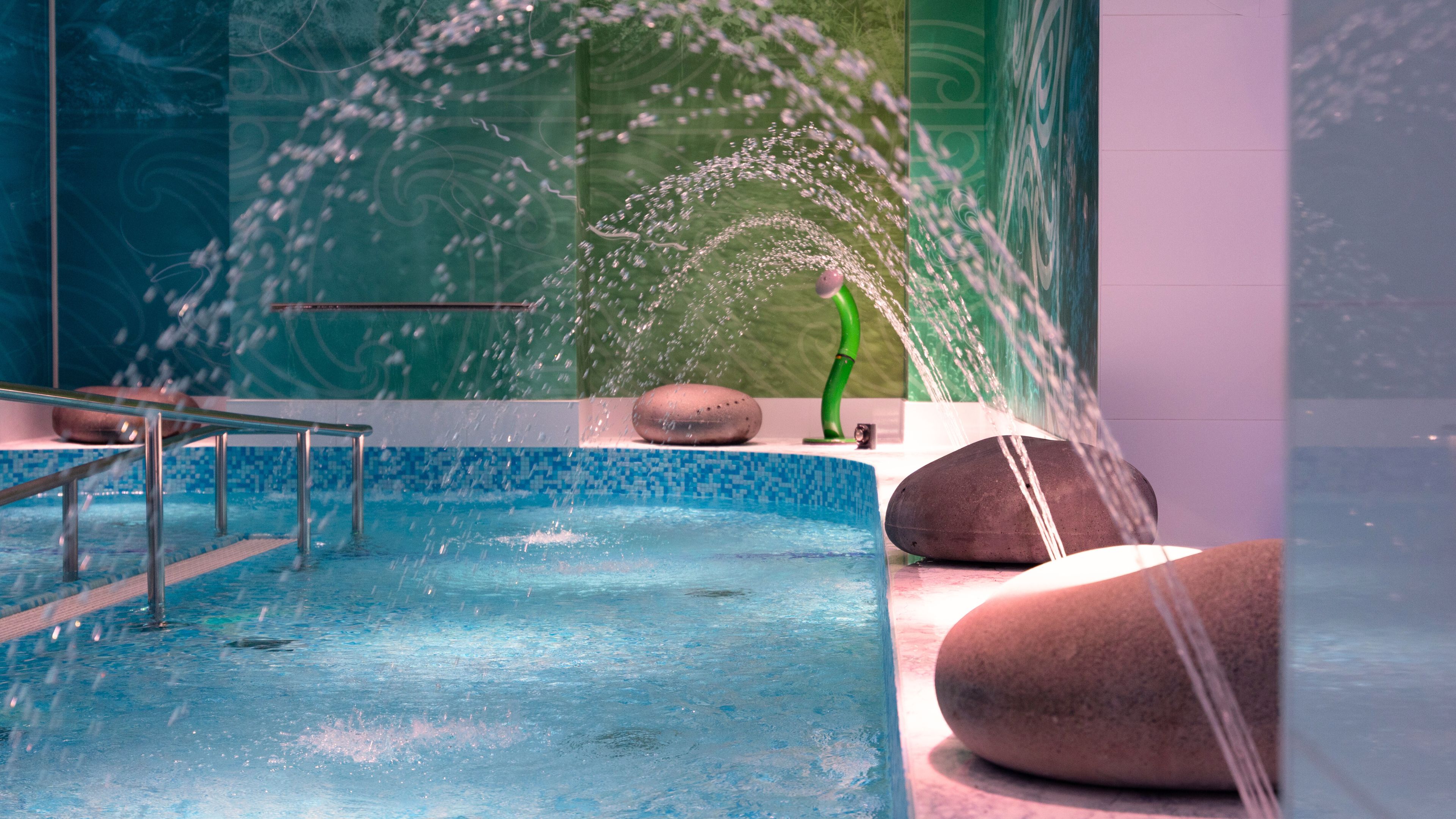 Indoor hydrotherapy pool with water jets and decorative rock features