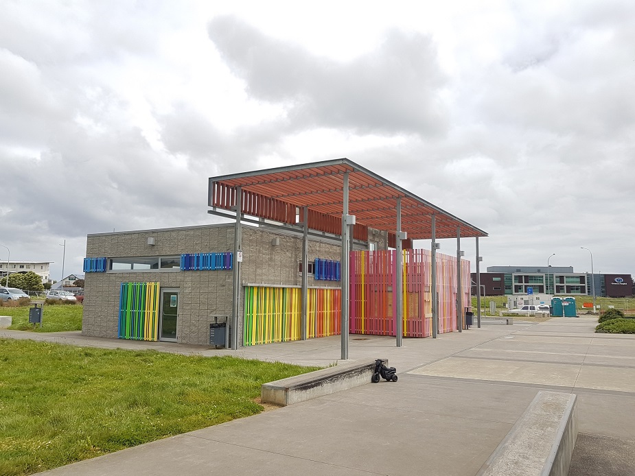 Contemporary concrete block activity centre with coloured vertical screen panels and covered entry