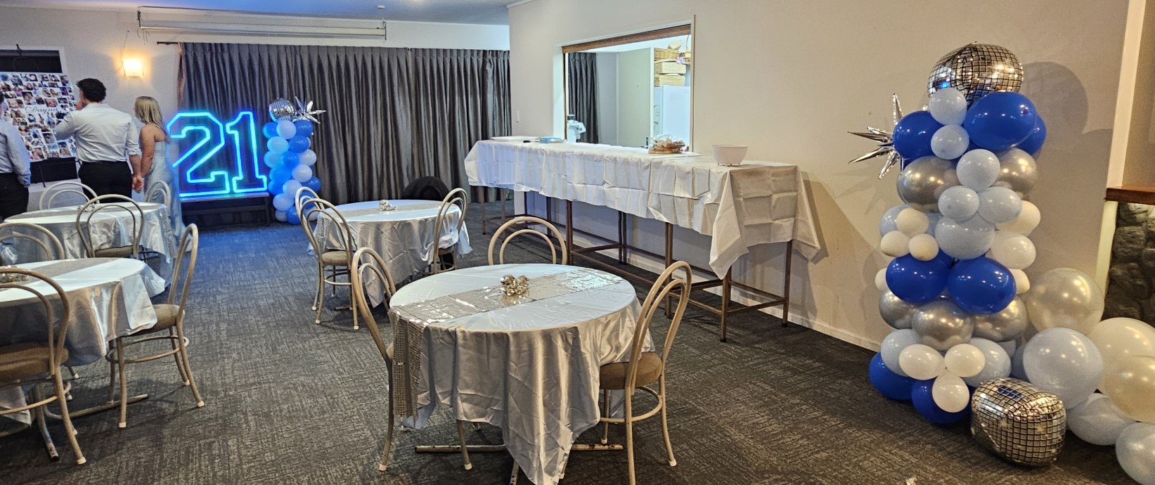 Function room dressed with balloons and round tables for a birthday celebration