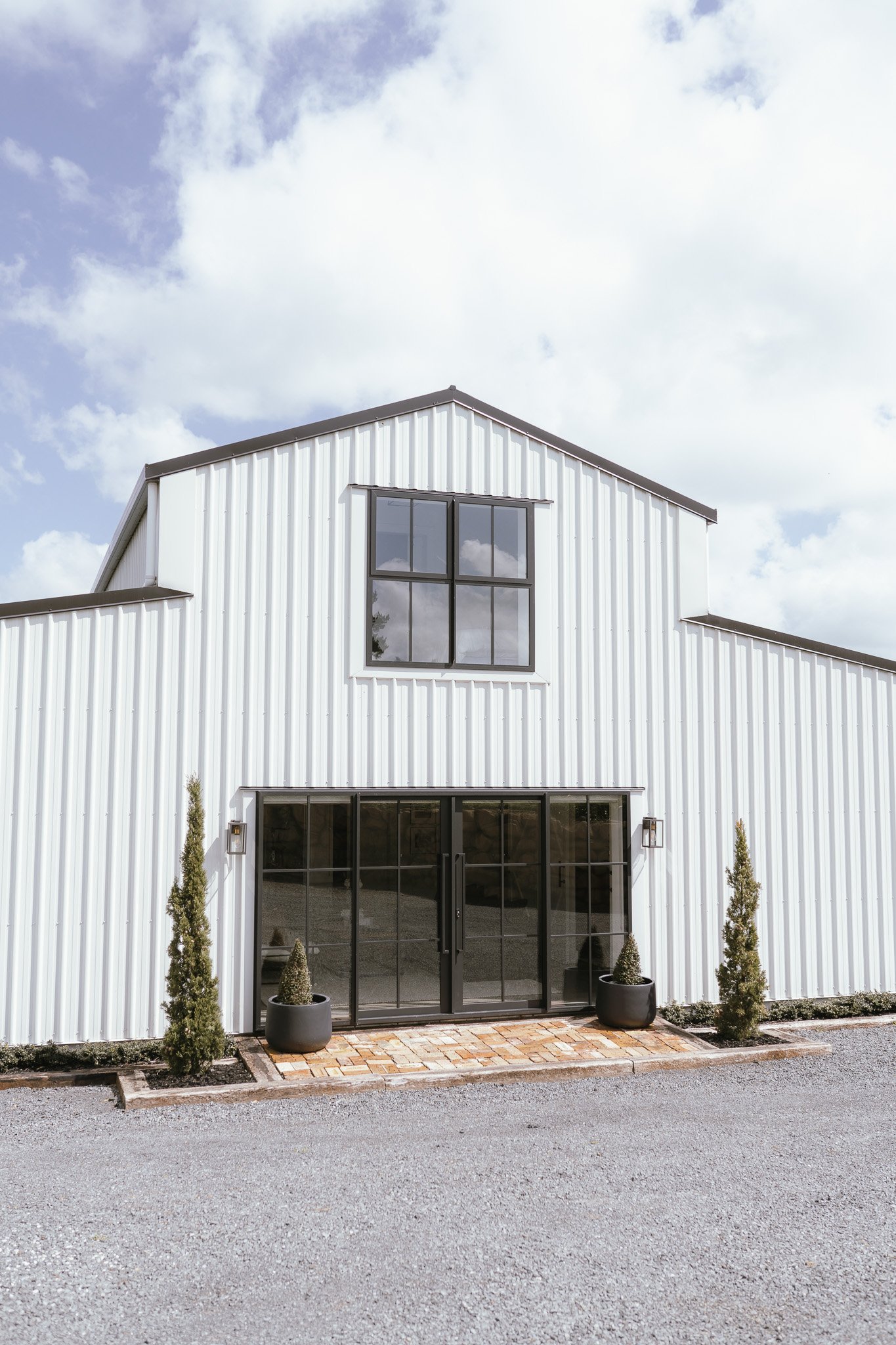 White steel barn building with black-framed glazed entry doors