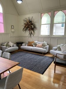 Bright room with arched windows, sofa seating, timber floor, and dining table