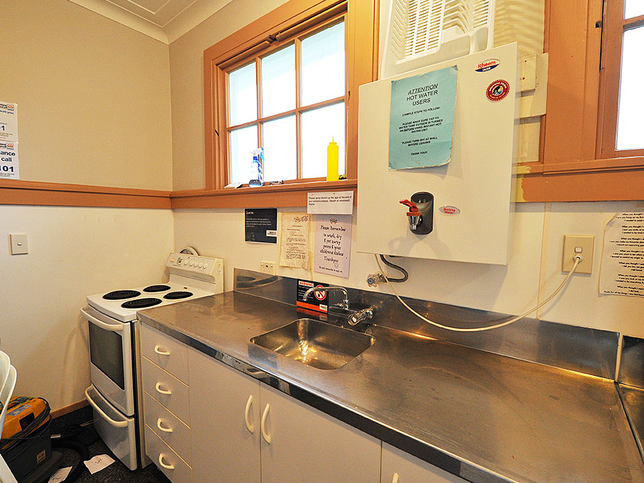 Small kitchen with stainless bench, sink, electric stove, and single window