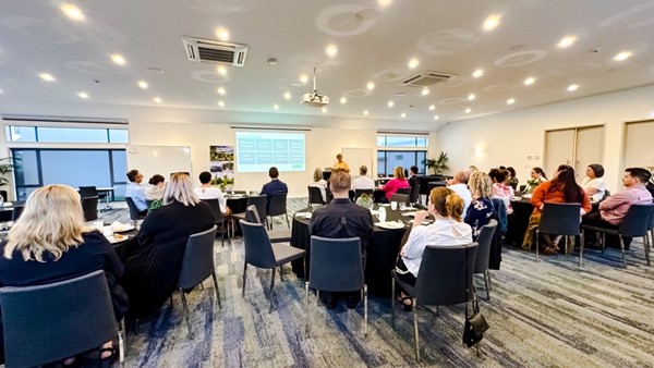 Conference room set theatre-style with round tables and presentation screen