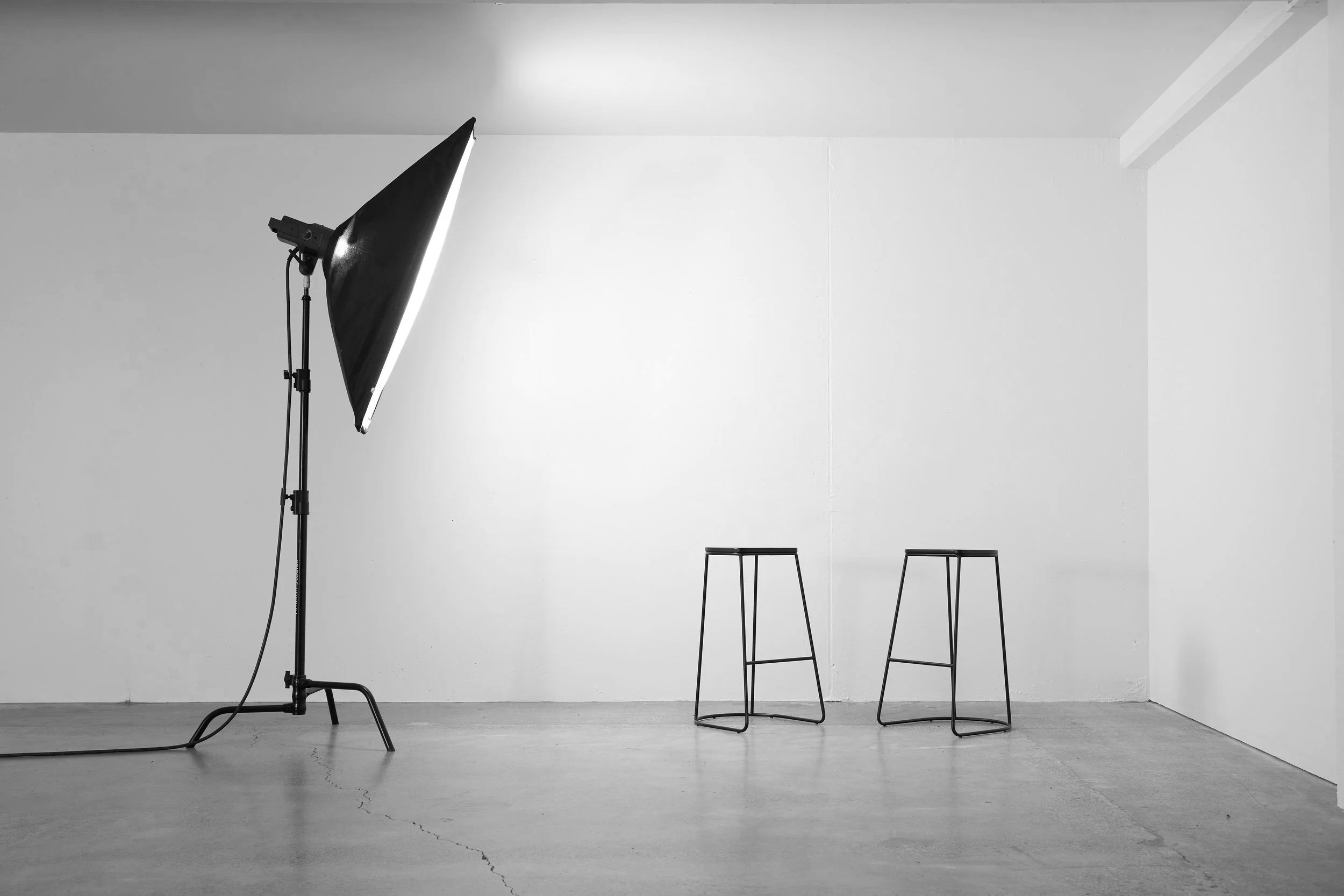 Studio space with softbox light, two metal stools, and white walls