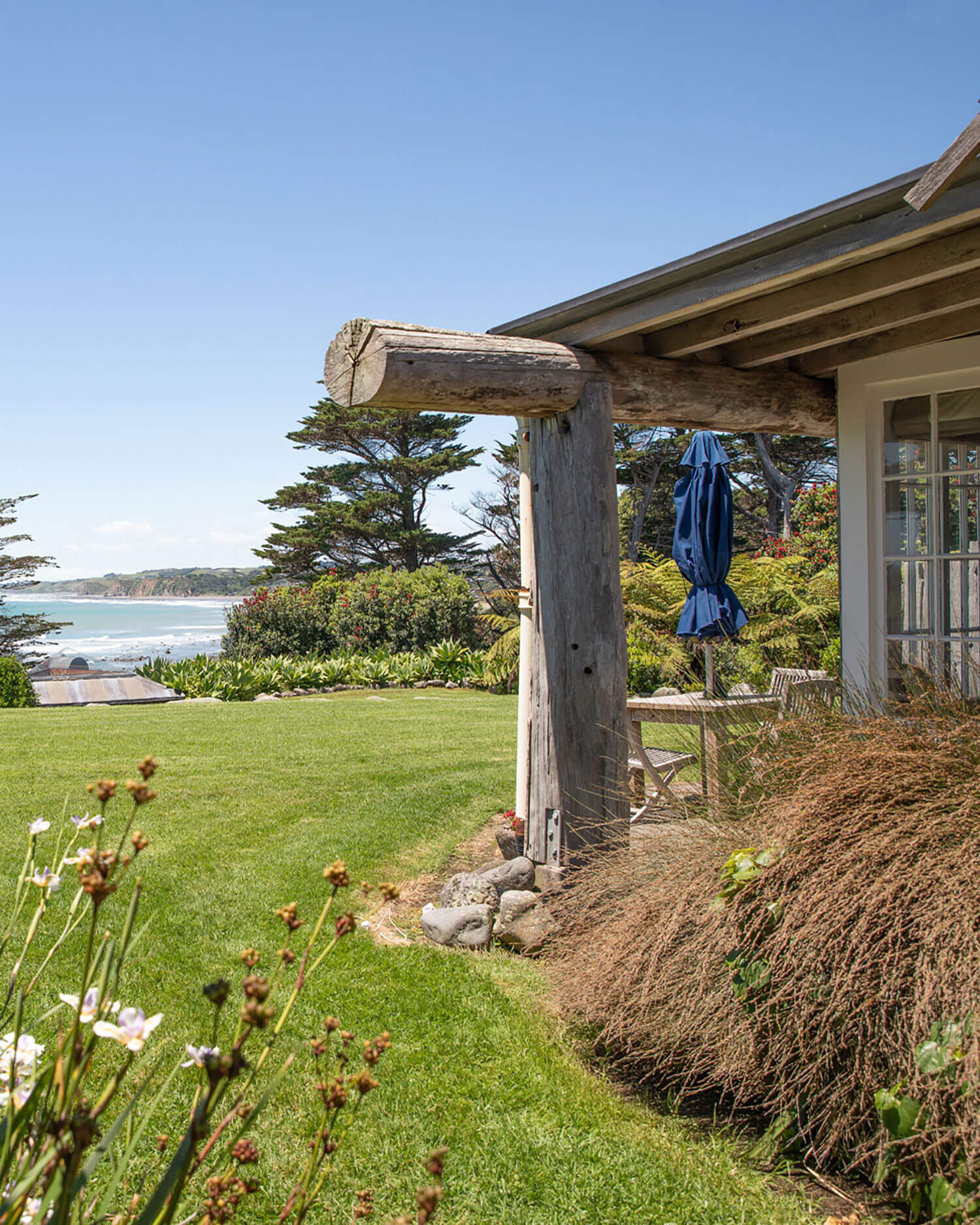 Villa verandah with rustic timber post gate, garden, and ocean view beyond