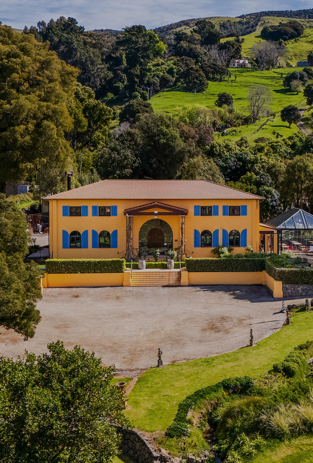 Aerial view of ochre winery building surrounded by trees and green hillside