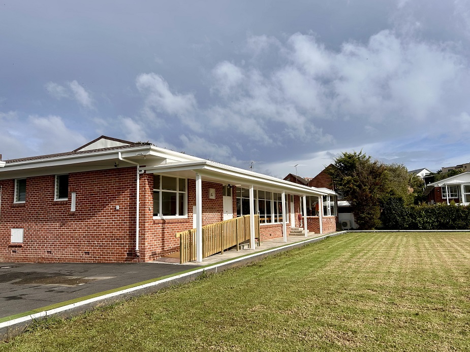 Single-storey brick clubhouse building with covered veranda and lawn
