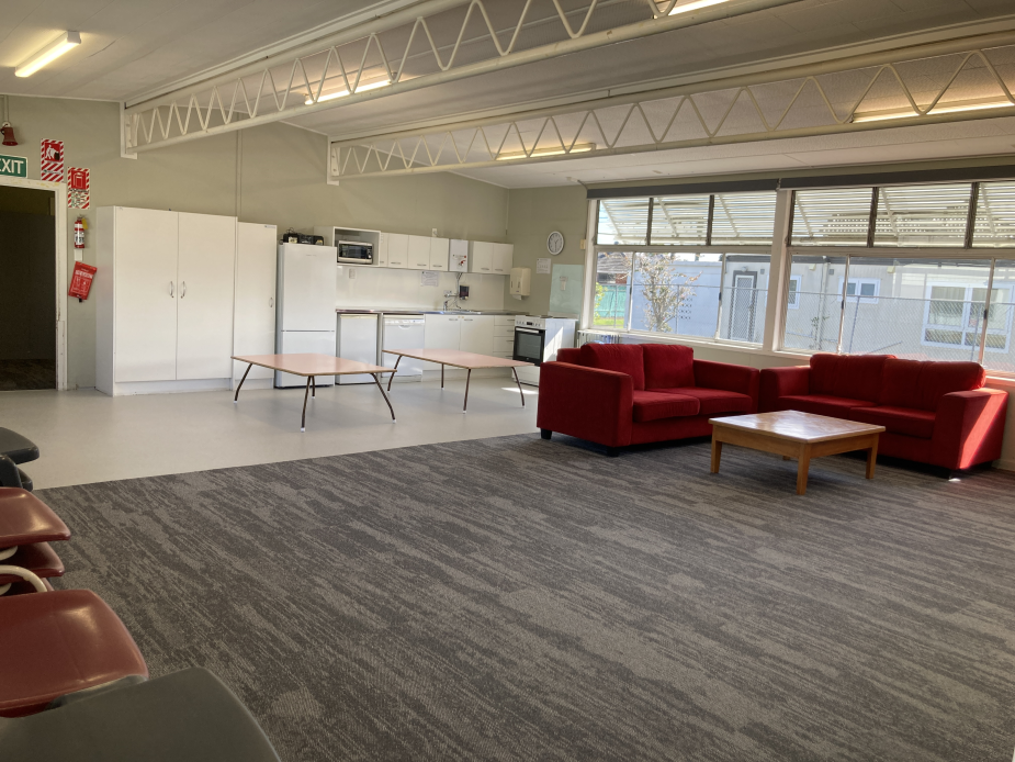 Community hall interior with kitchen bench, red sofas and carpet tiles