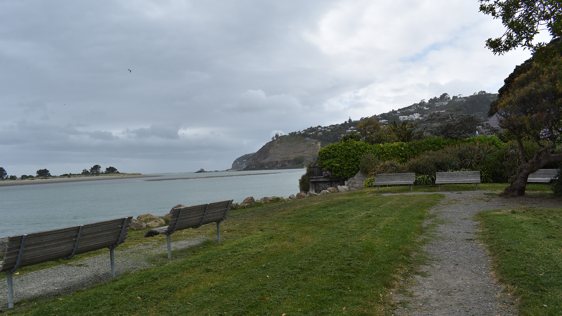 Grassed reserve with benches alongside an estuary and headland