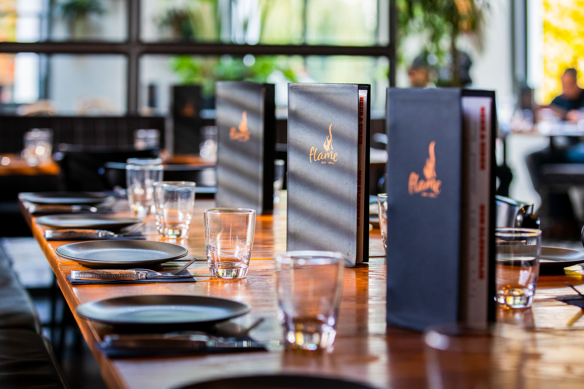 Restaurant dining setup with set table, menus, and large windows