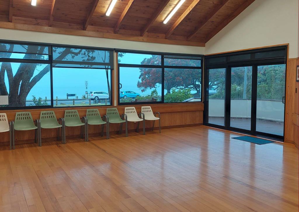 Foyer area with timber walls, polished floor, chairs along windows overlooking outside
