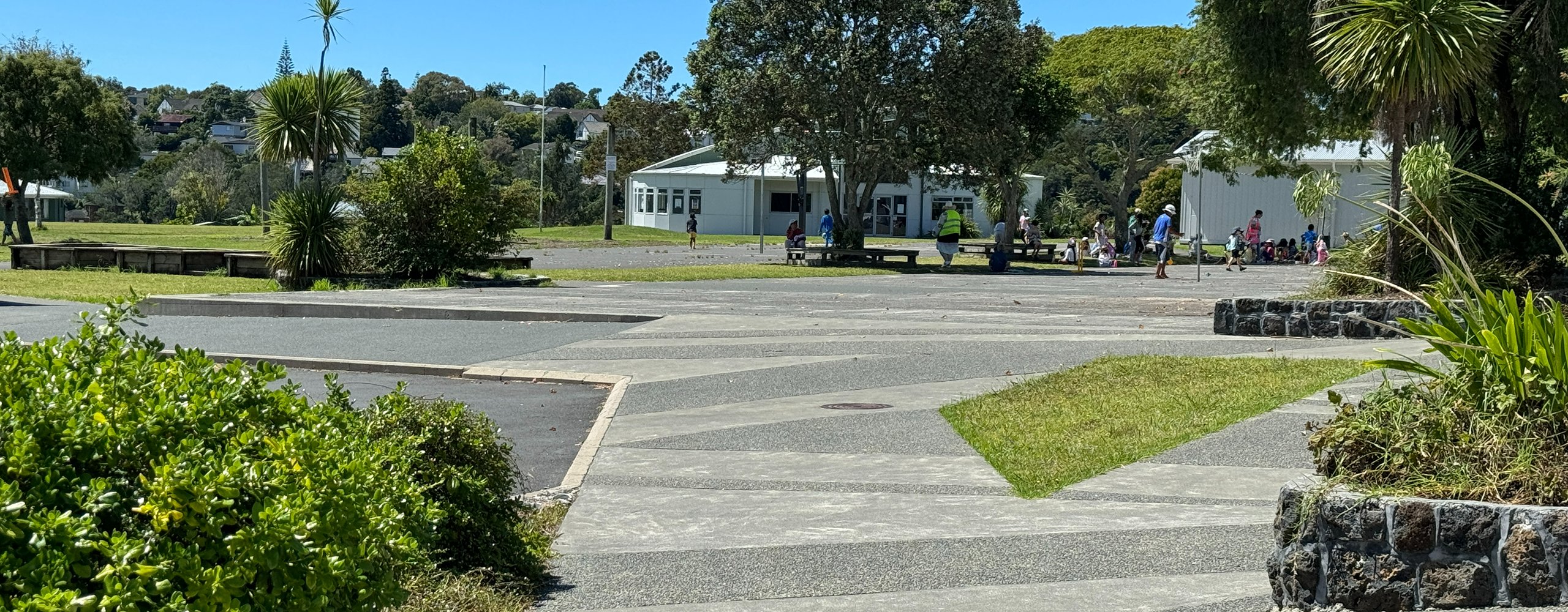School grounds with paved courtyard, lawn, and buildings in background