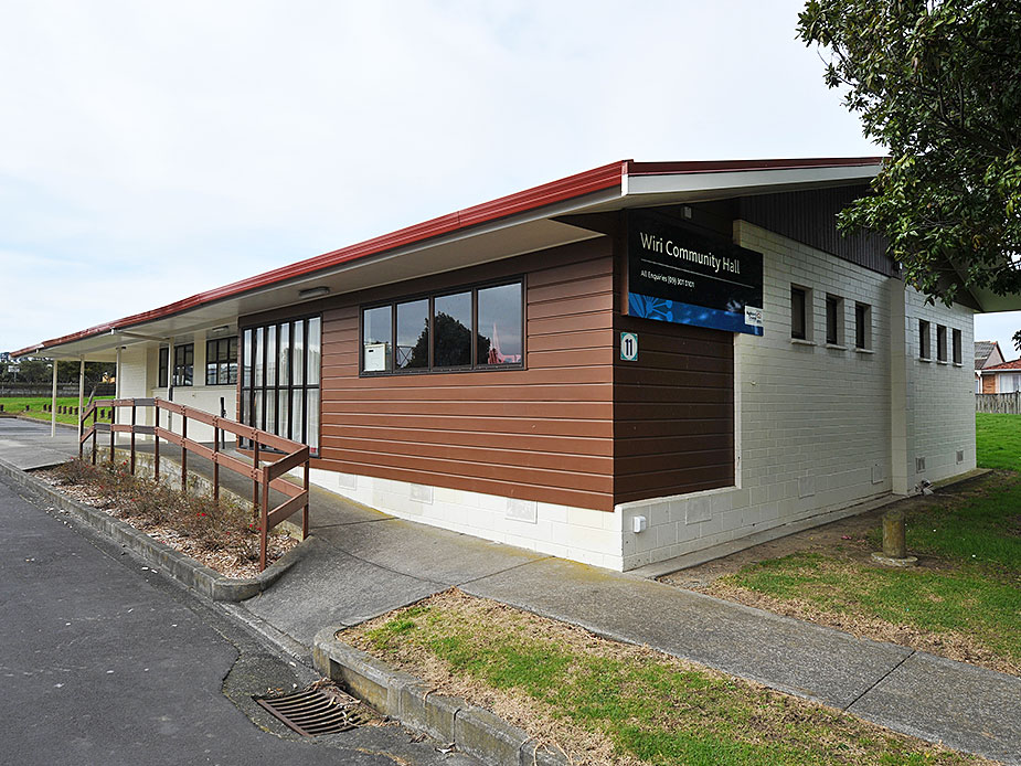 Single-storey community hall with red roof trim and accessible ramp