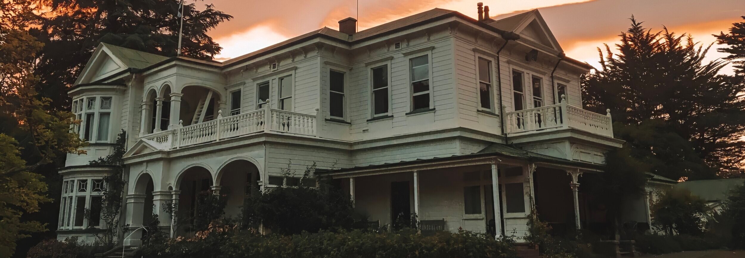 Heritage homestead exterior at dusk with warm sky and veranda detail