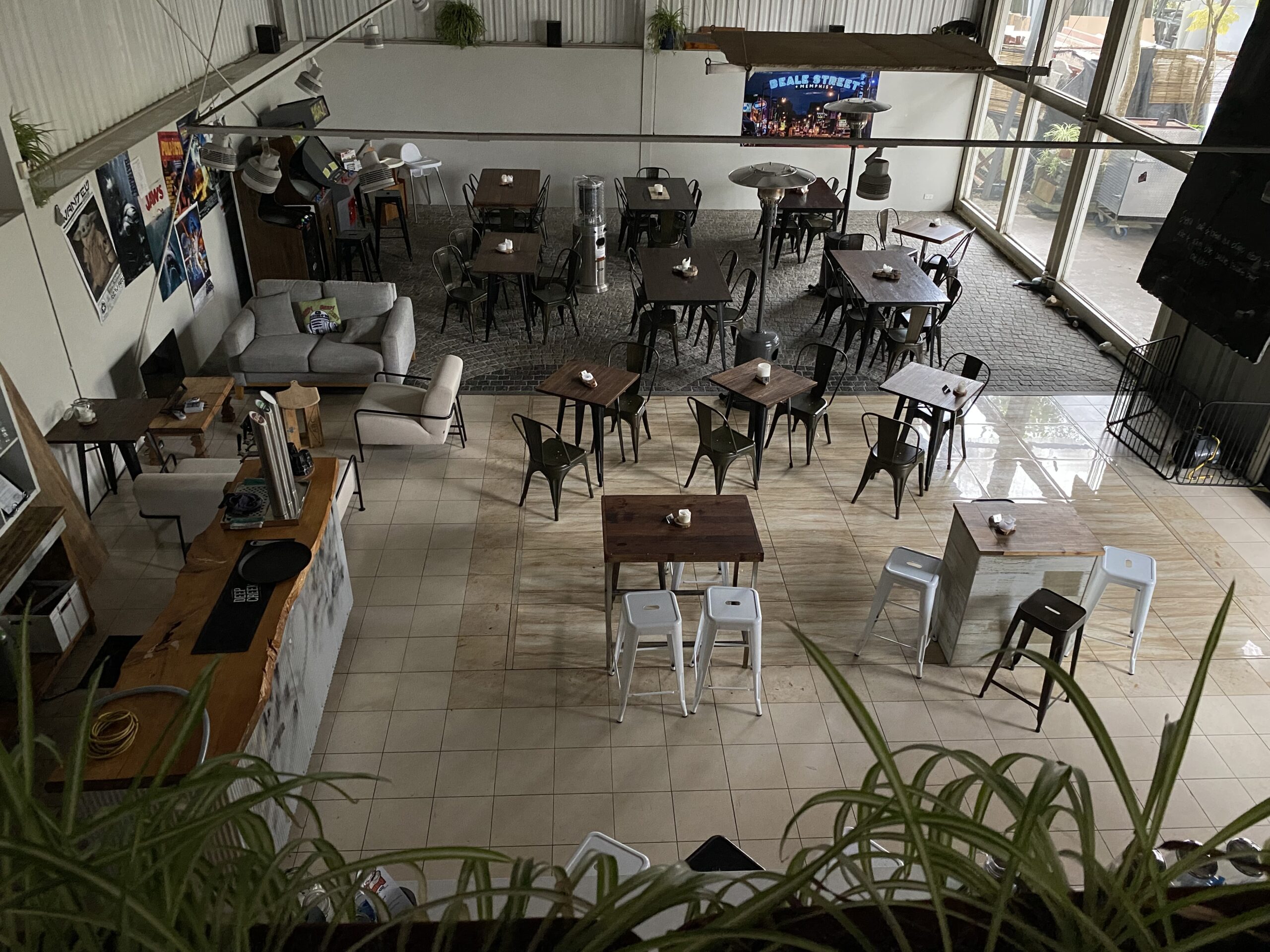Industrial dining space viewed from above with metal chairs, wooden tables, and mezzanine