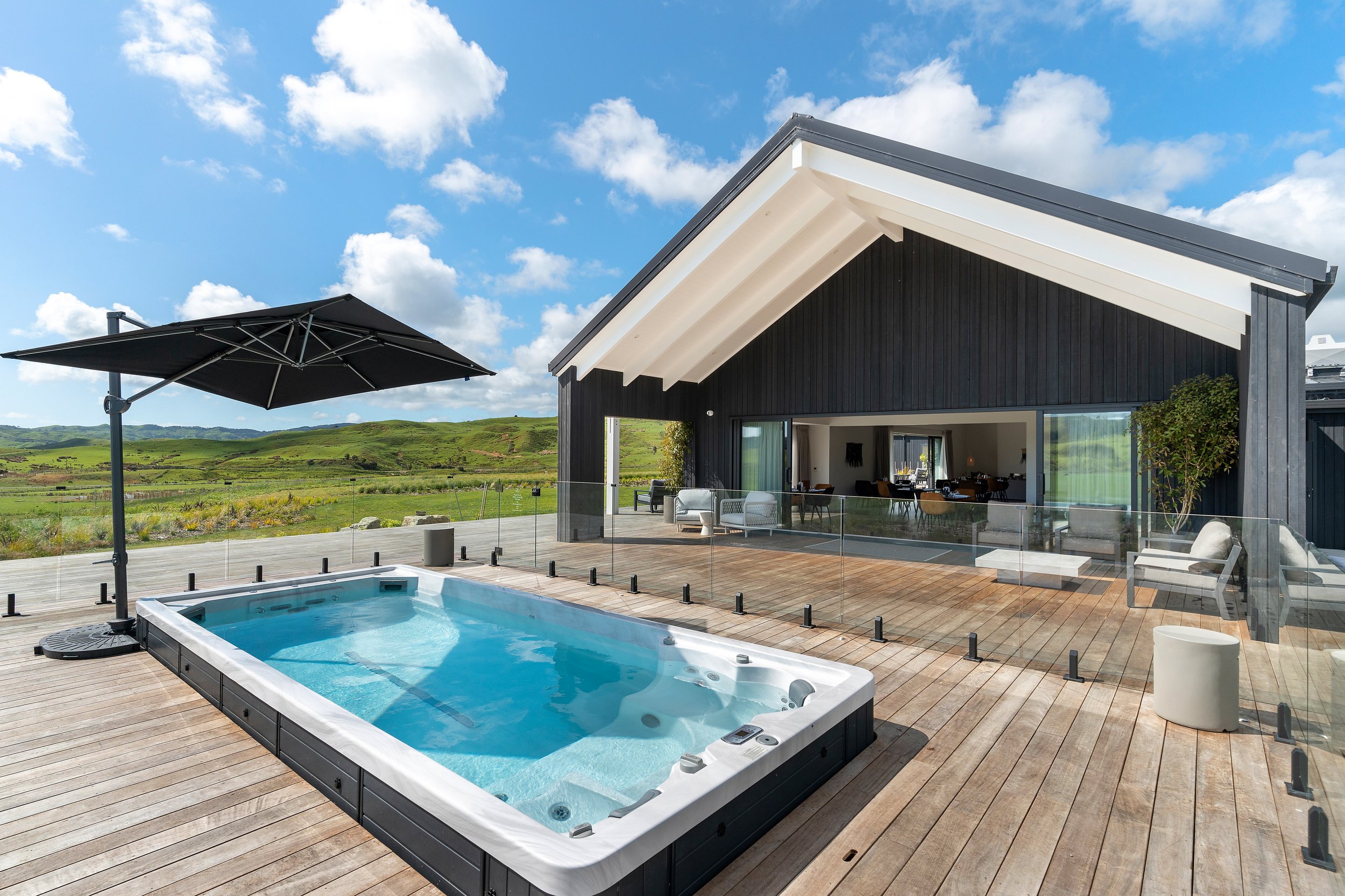 Timber deck with pool, outdoor furniture and rural hill views