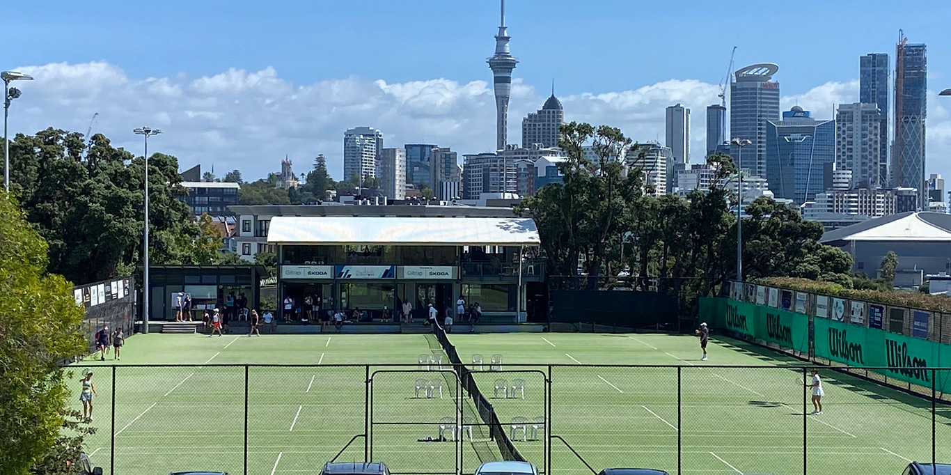 Tennis courts with pavilion building and Auckland city skyline behind