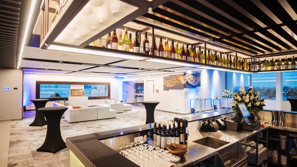 Hotel bar area with illuminated bottle display and open function lounge beyond