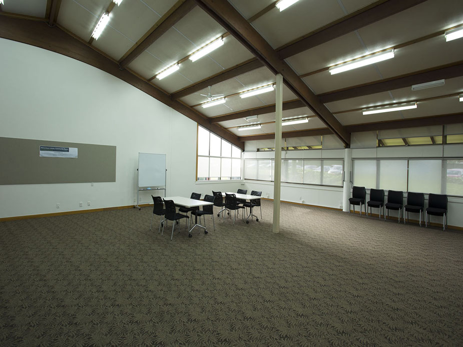 Large community room with curved timber-beam roof and tables set for a meeting