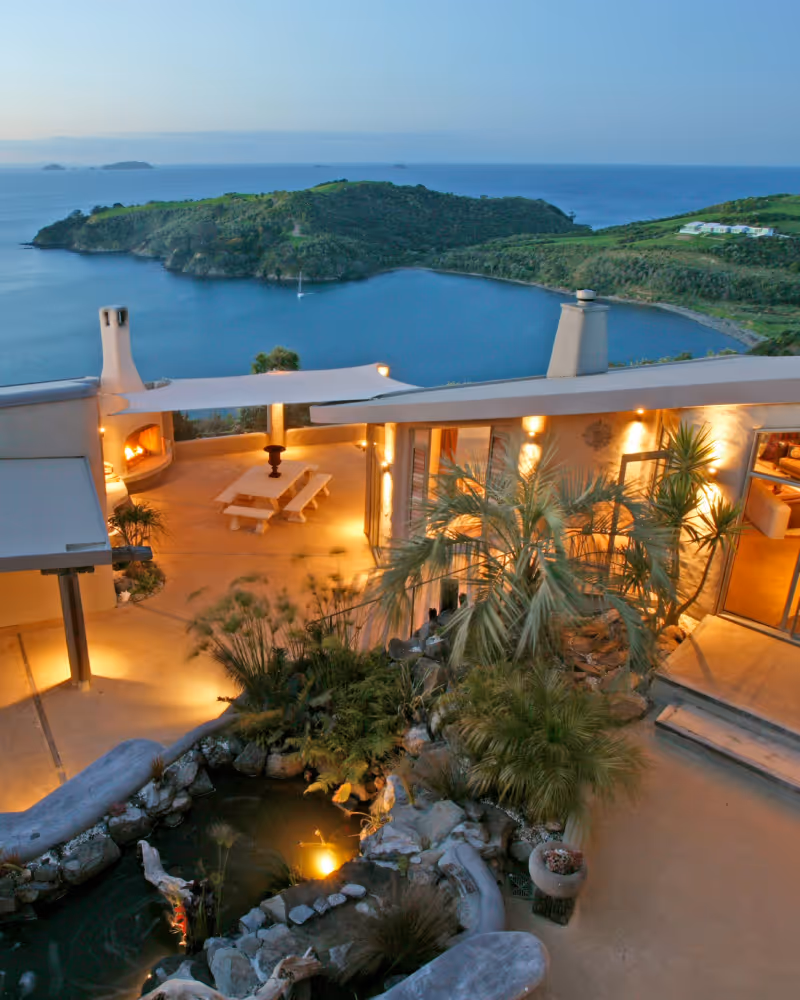Elevated lodge terrace at dusk with ornamental pond and sea views