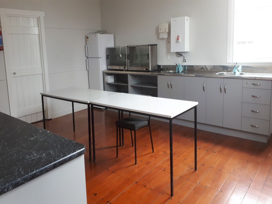Basic kitchen with grey cabinetry, stainless bench, fridge, and polished timber floor