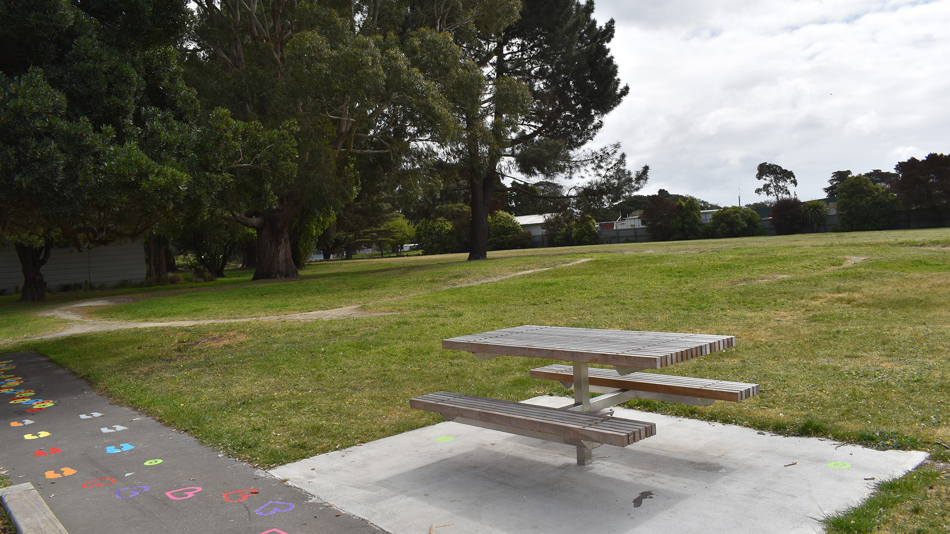 Park with picnic table, trees and painted pathway markings in foreground