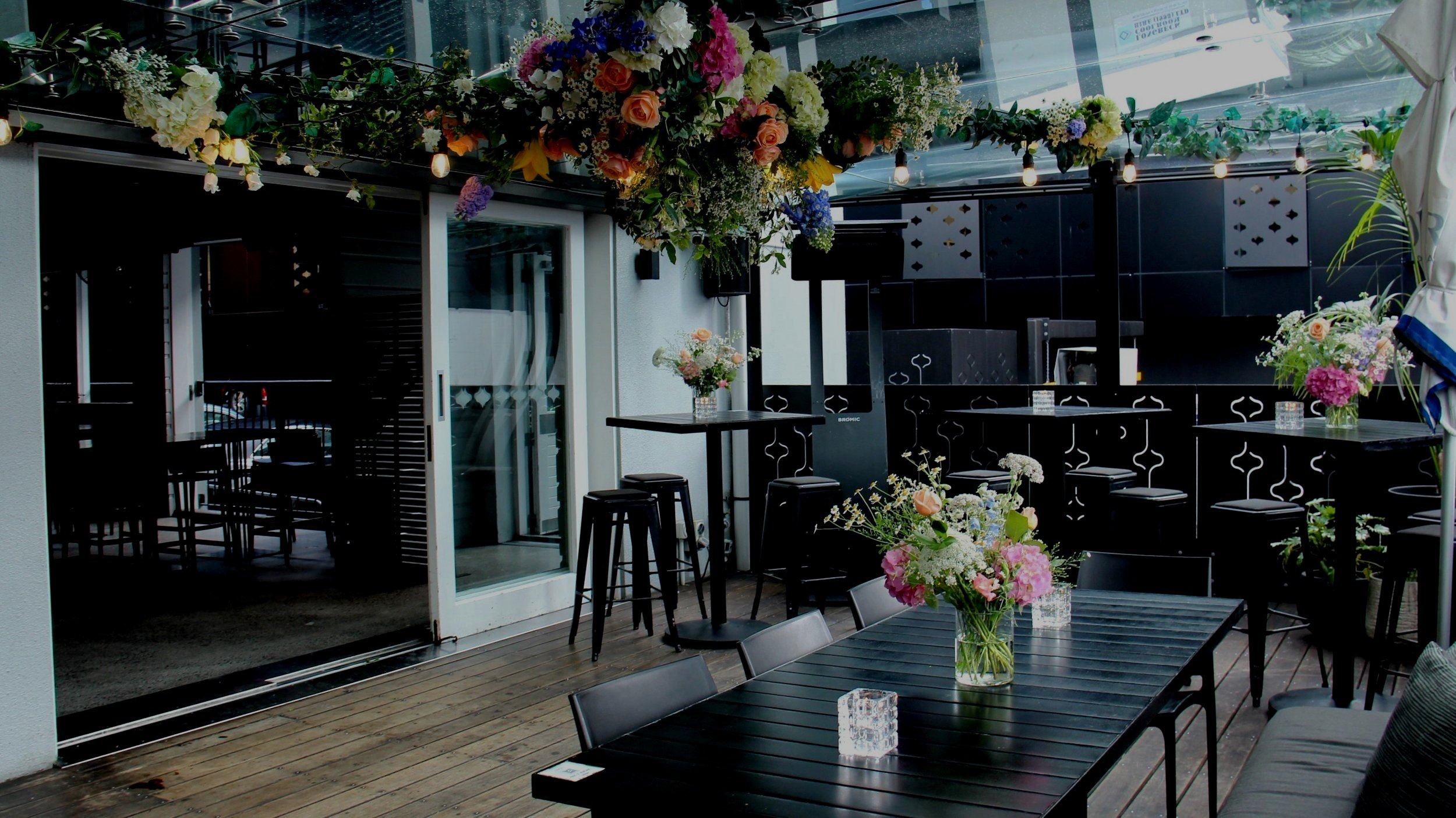 Outdoor terrace set with black tables and flower arrangements for an event