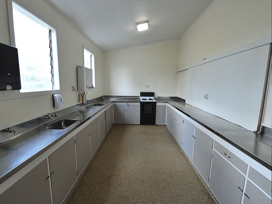 Hall kitchen with stainless steel benchtops and white cabinets
