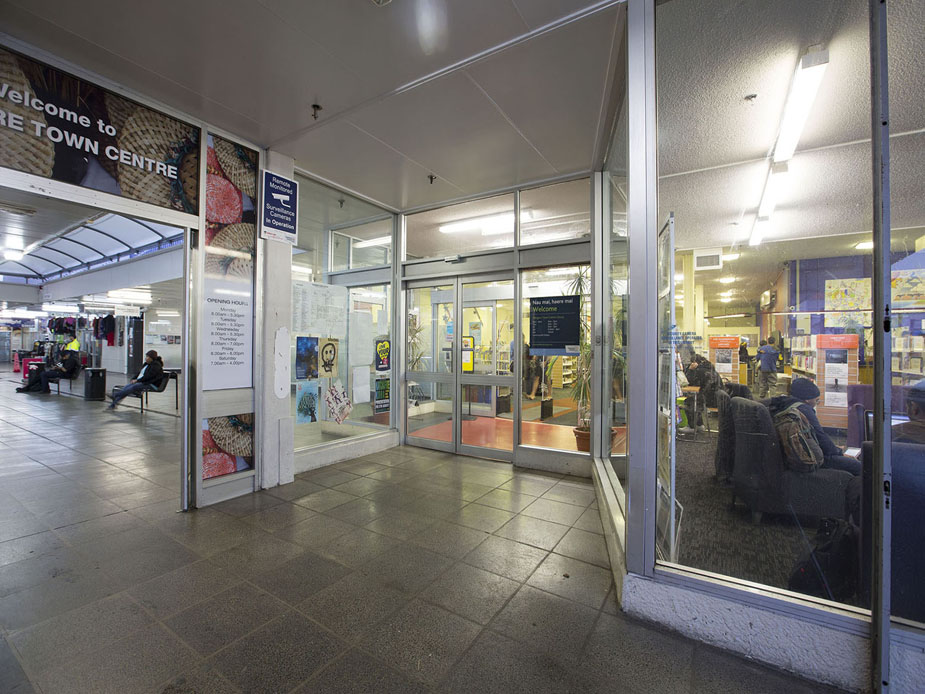 Library entrance viewed from covered walkway with signage visible inside
