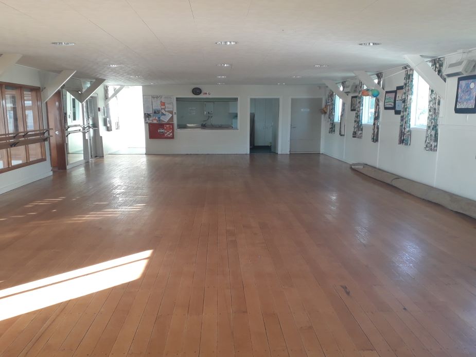Carpeted room with curtains, exit door, and empty floor space