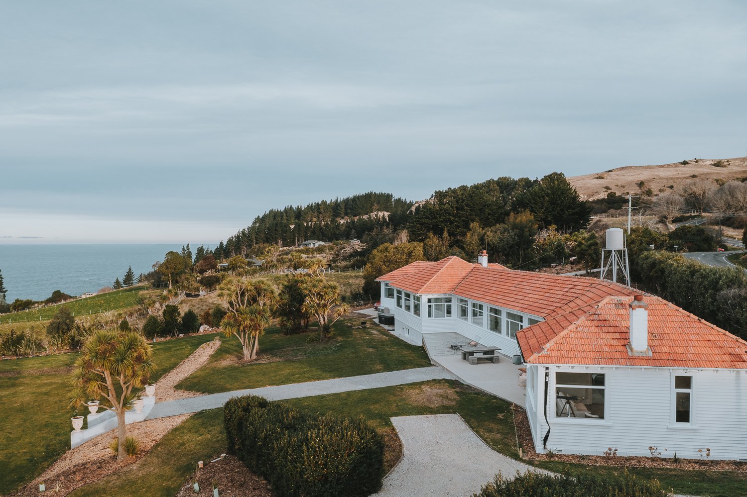Aerial view of white villa with terracotta roof on coastal hillside