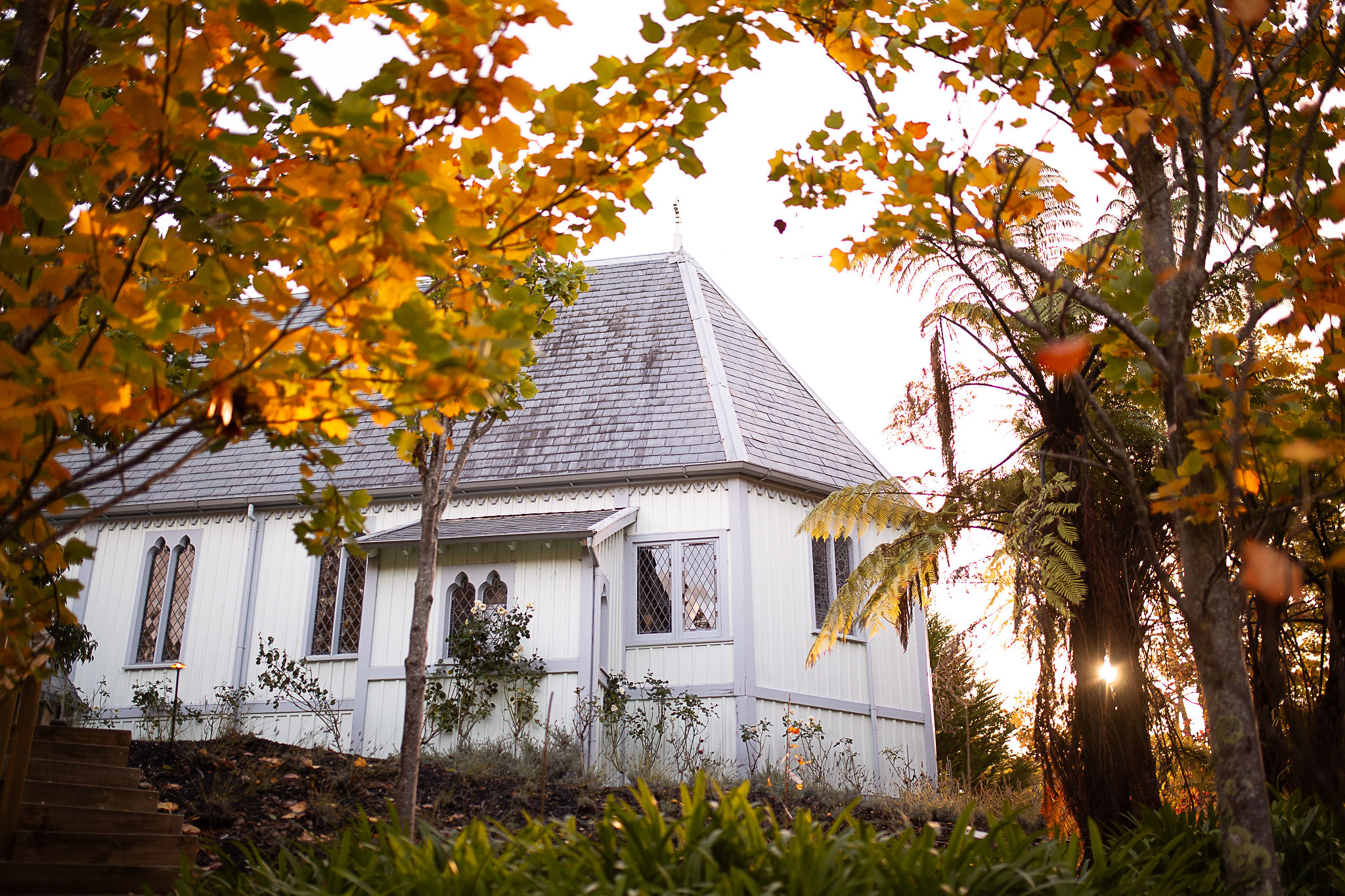 White timber chapel with steeply pitched roof and decorative bargeboards, framed by autumn trees