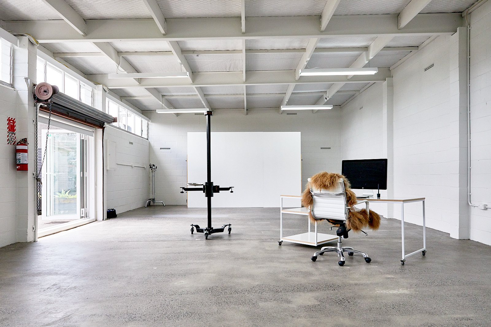 Open white industrial space with concrete floor, photography backdrop and desk