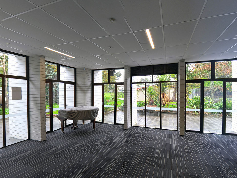 Light-filled foyer with covered grand piano and garden views through full-height glazing