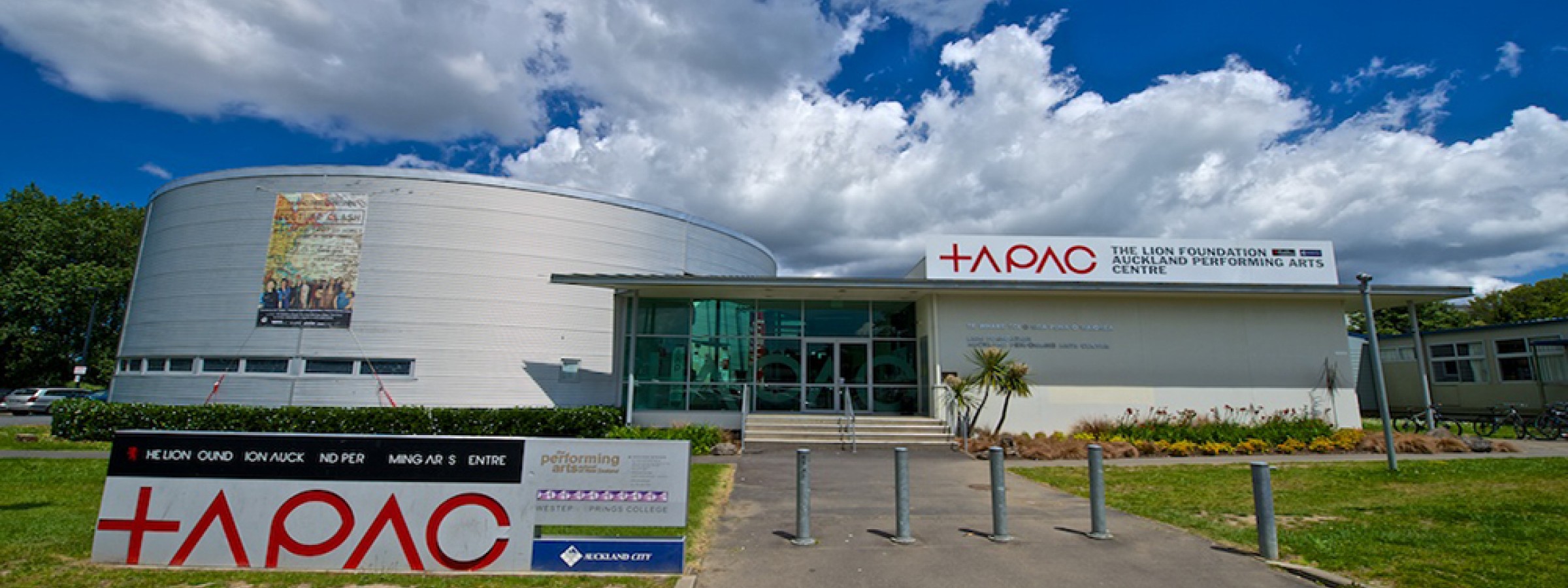 Performing arts centre exterior with curved facade and TAPAC signage under blue sky