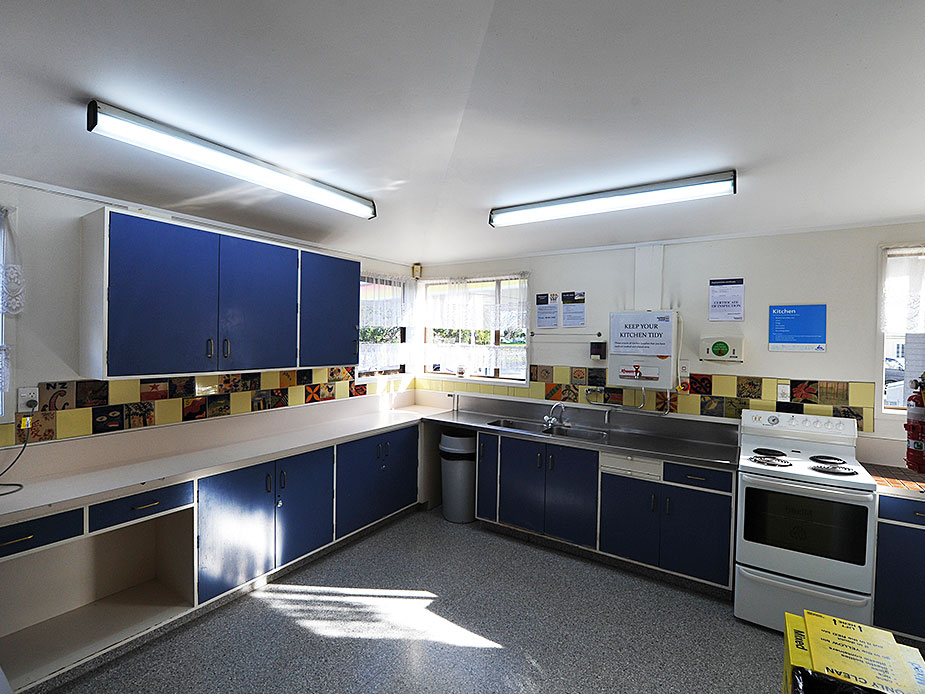 Community kitchen with blue cabinetry, stainless sink, and decorative tiled splashback
