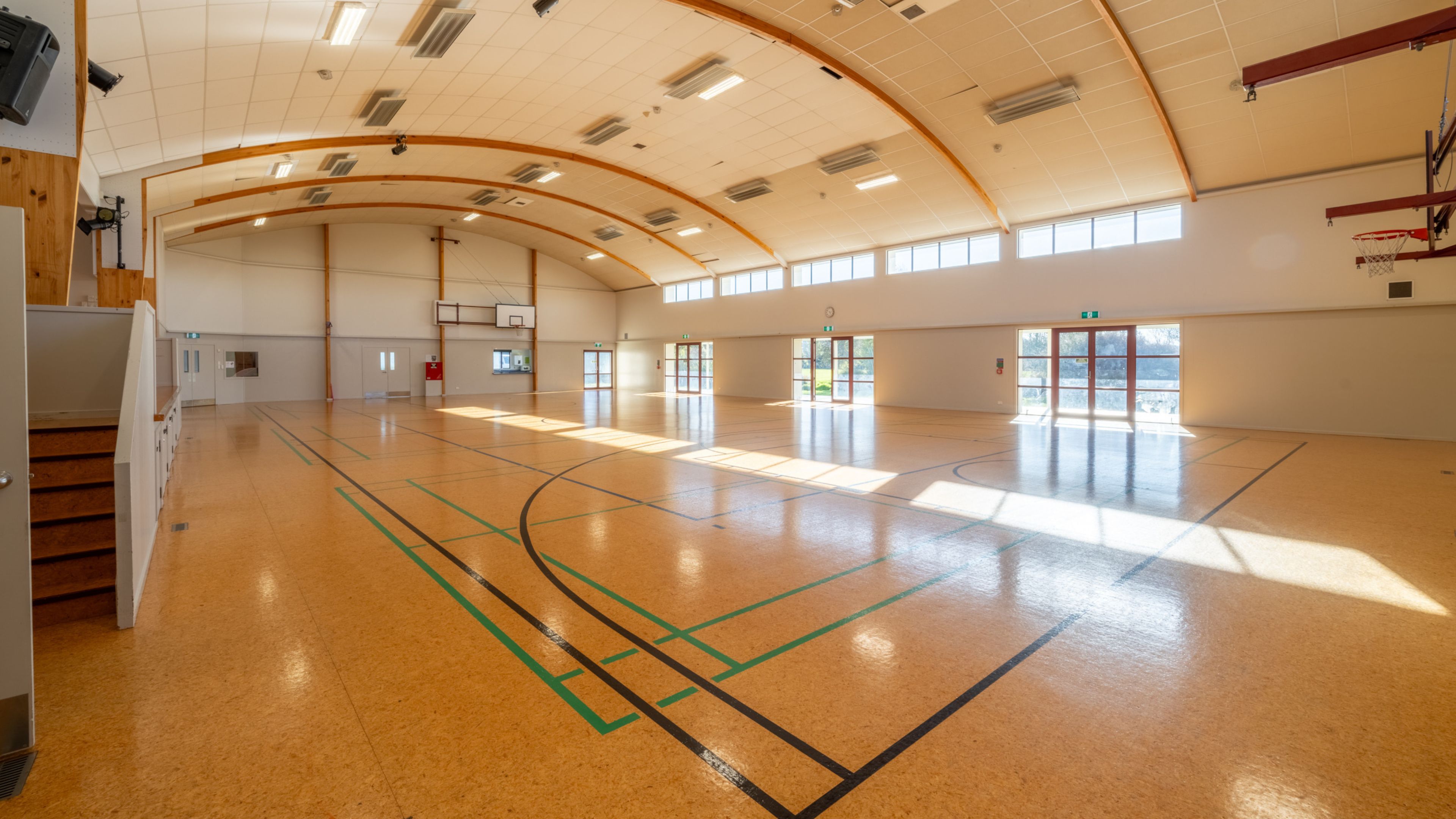 Large sports hall with curved timber roof and polished floor