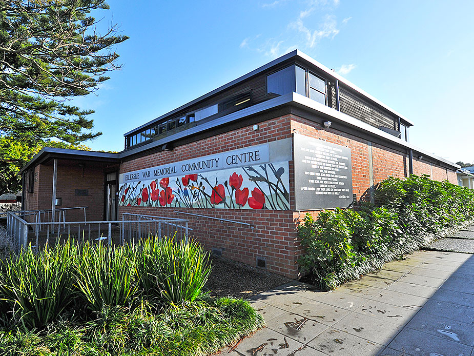 Brick community centre showing side elevation with poppy mural and garden planting