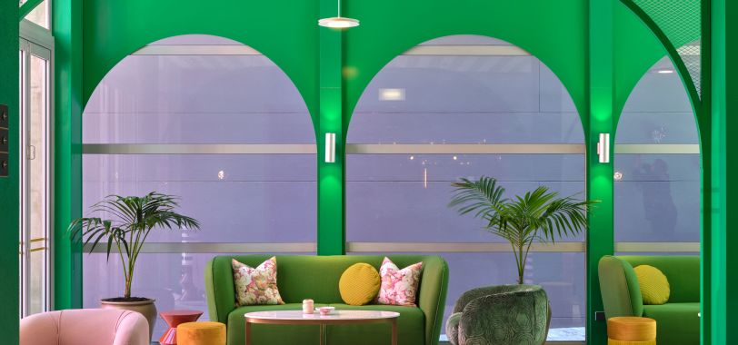 Vibrant green lounge area with arched alcoves, green sofas and colourful cushions