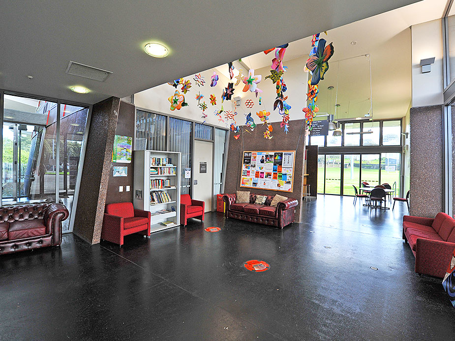 Foyer with dark polished floor, red seating, bookshelves, and hanging decorations